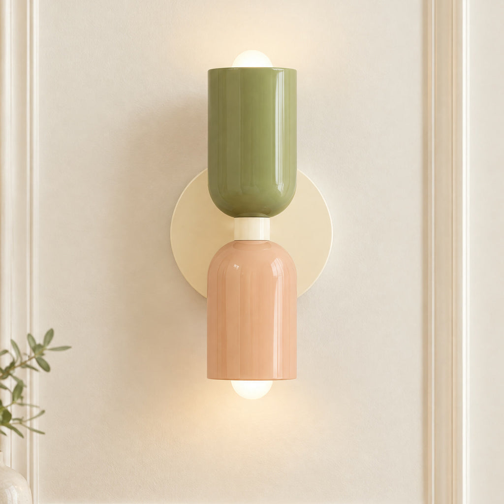 Applique murale couleur vert sauge et rose à 2 lumières, en gros plan sur un mur à moulures