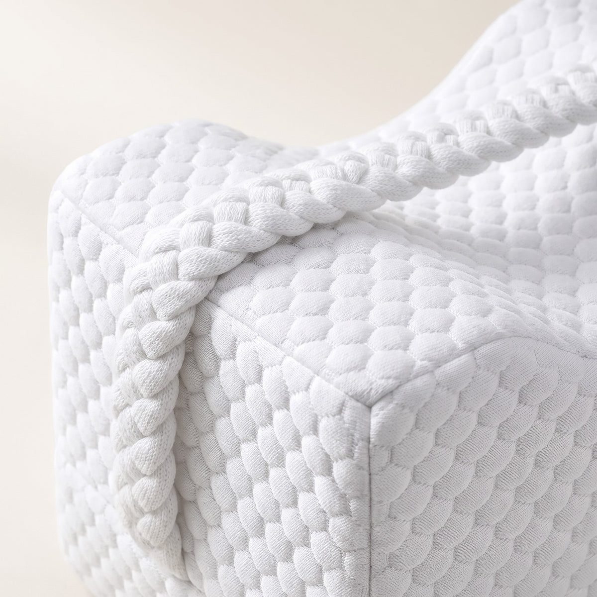 Gros plan sur la housse alvéolée et la poignée tressée du coussin cale-genoux Maison Reposéa