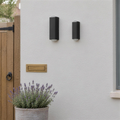 Grand et petit modèles de l'applique extérieure noire côte à côte sur une façade, en plein jour