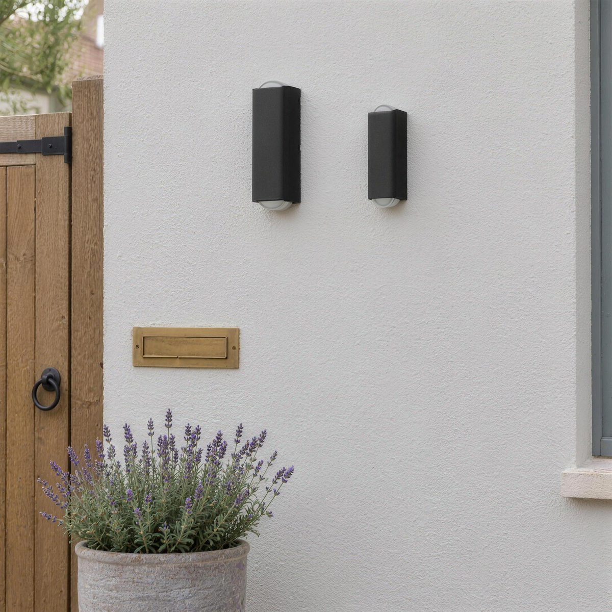Grand et petit modèles de l'applique extérieure noire côte à côte sur une façade, en plein jour