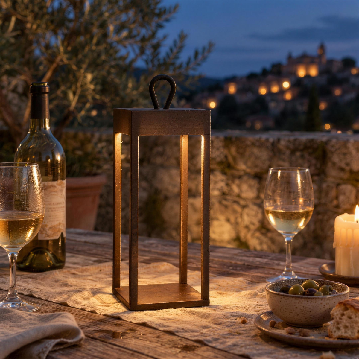Lanterne LED sans fil rouille allumée sur une table de terrasse en teck, le soir