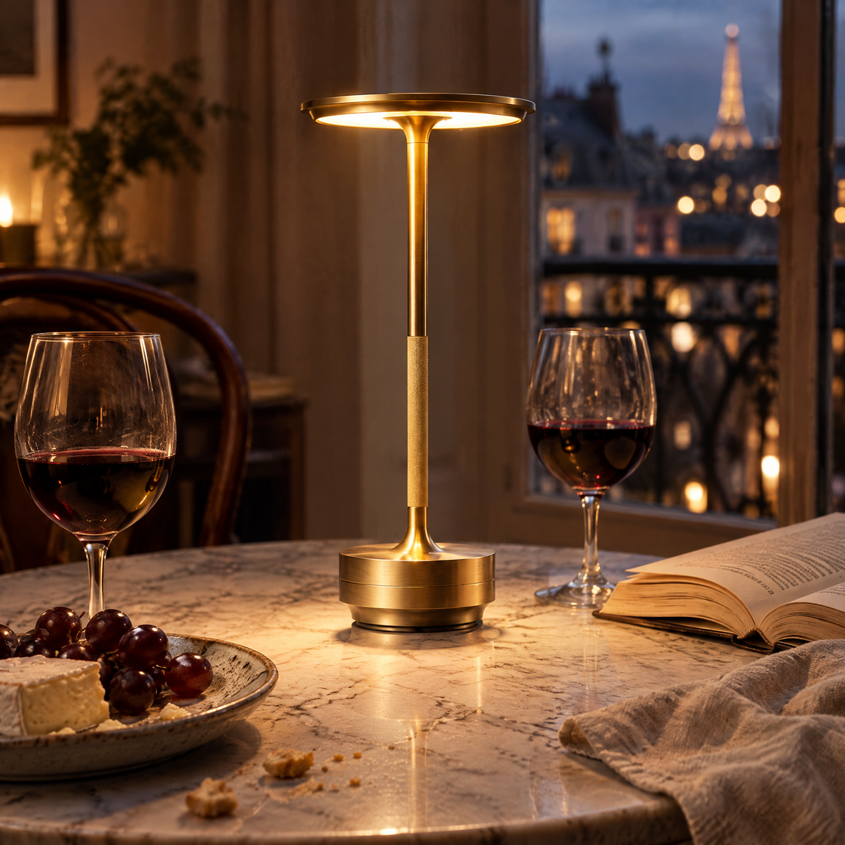 Lampe de table sans fil dorée allumée sur une table de bistrot en marbre, le soir
