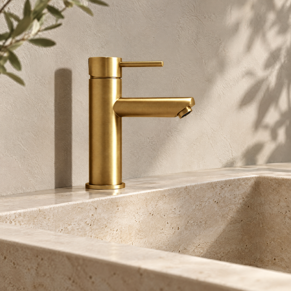 Mitigeur lavabo monotrou doré brossé sur un lavabo en travertin