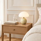 Lampe champignon en céramique vert amande sur une table de chevet en chêne