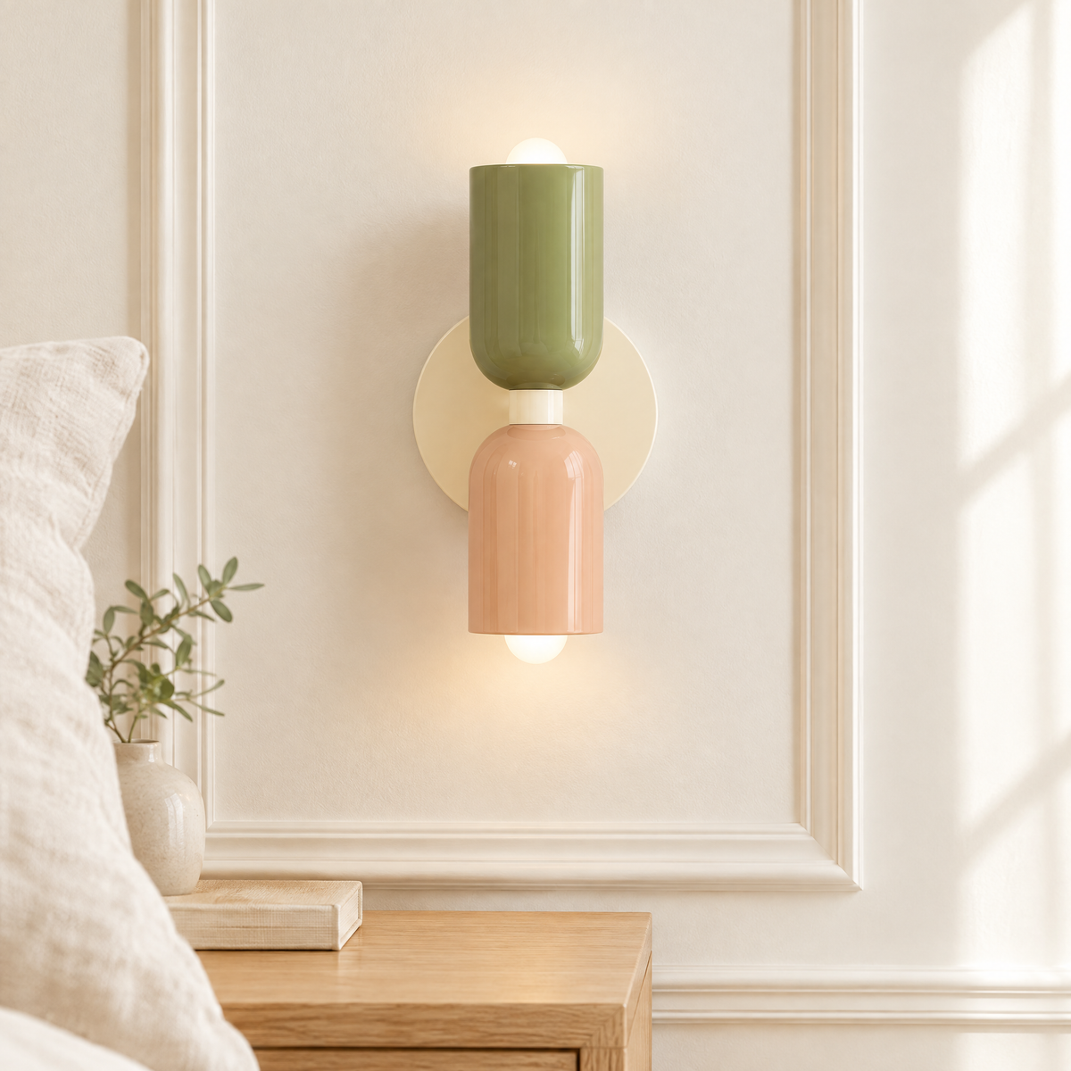 Applique murale macaron vert sauge et rose allumée au-dessus d'une table de chevet