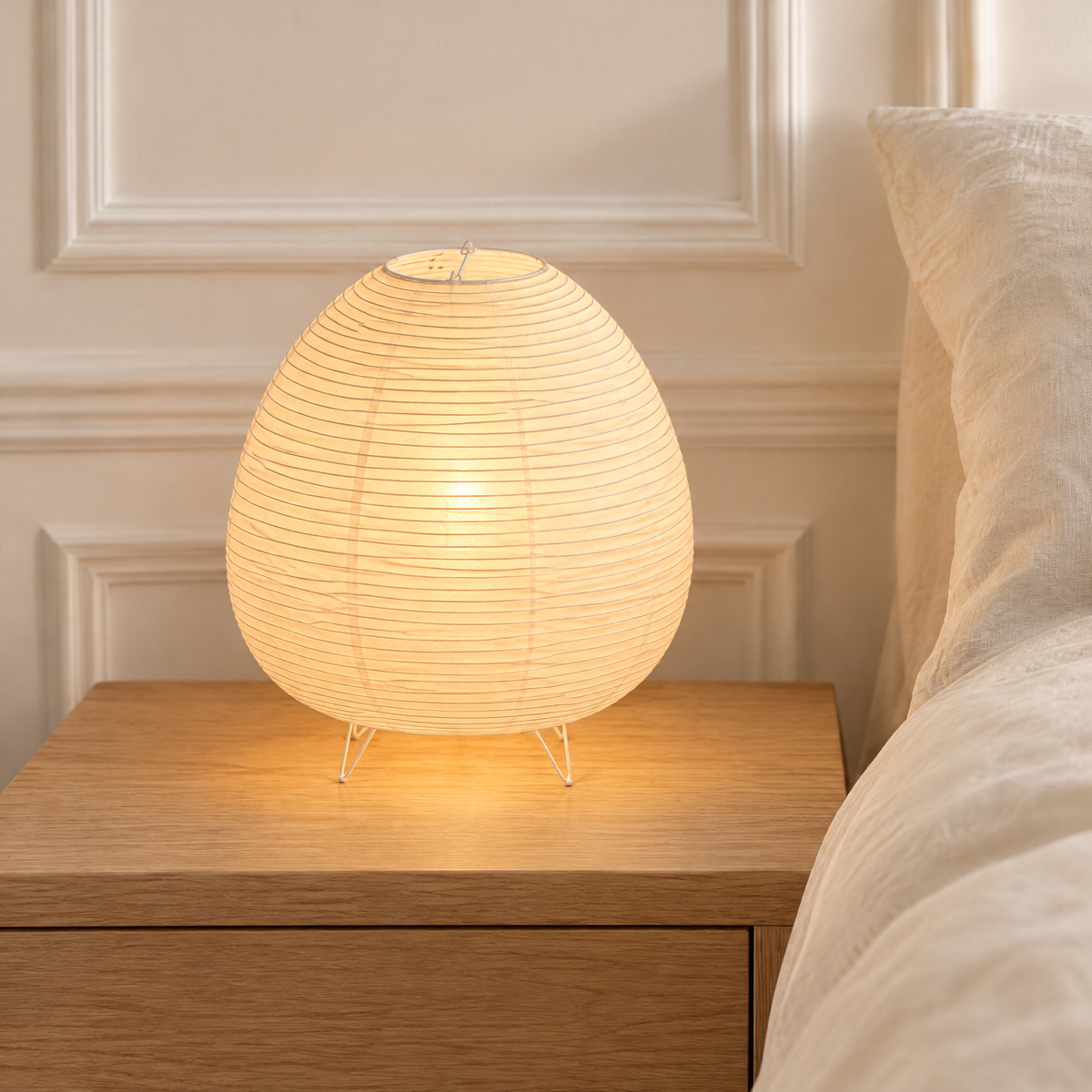 Lampe de chevet en papier de riz allumée sur une table de chevet en chêne