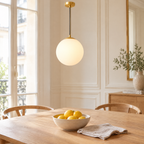 Suspension boule opaline au-dessus d'une table à manger en chêne