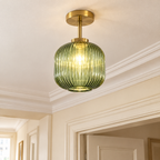 Plafonnier en verre strié vert et laiton allumé, au plafond d'un couloir à moulures
