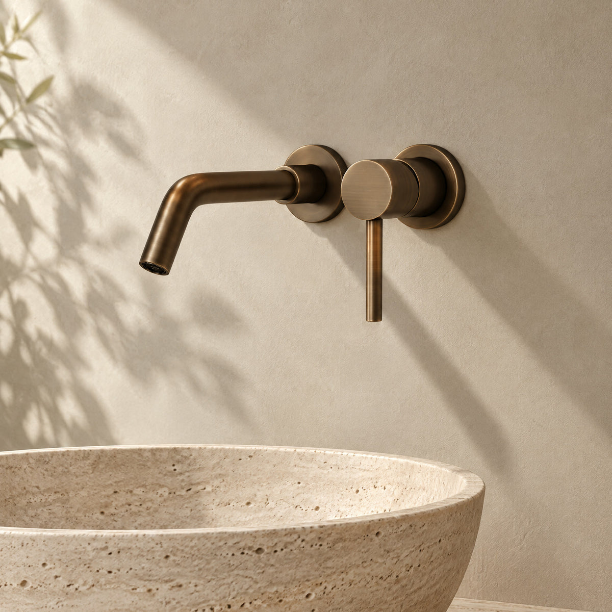 Mitigeur lavabo mural encastré bronze brossé au-dessus d'une vasque en travertin
