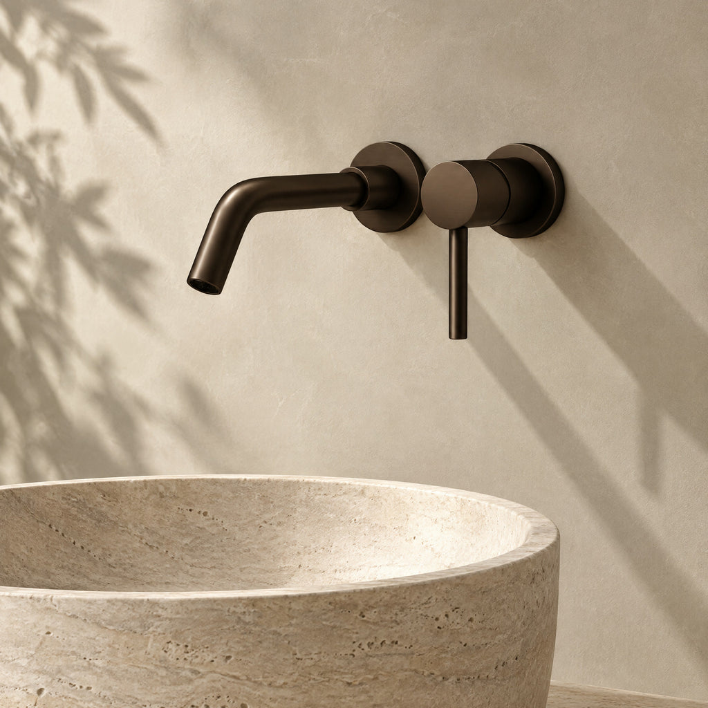 Mitigeur lavabo mural encastré bronze profond au-dessus d'une vasque en travertin