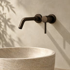 Mitigeur lavabo mural encastré bronze profond au-dessus d'une vasque en travertin