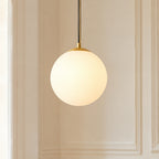 Suspension boule en verre opaline blanche allumée, pavillon doré, en gros plan